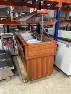 Wooden salad bar with plastic sneeze guard used